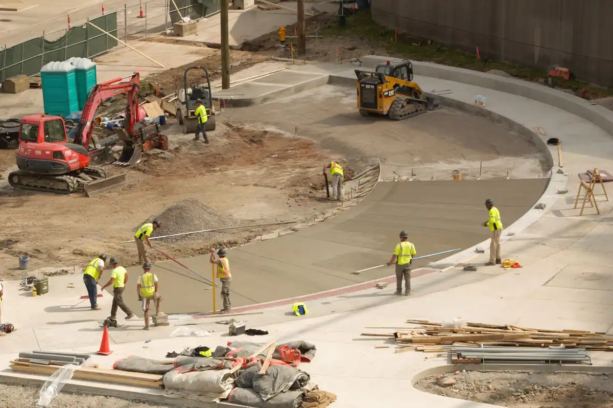 Commercial concrete flatwork crew screeding a large curved pour beside new curbs