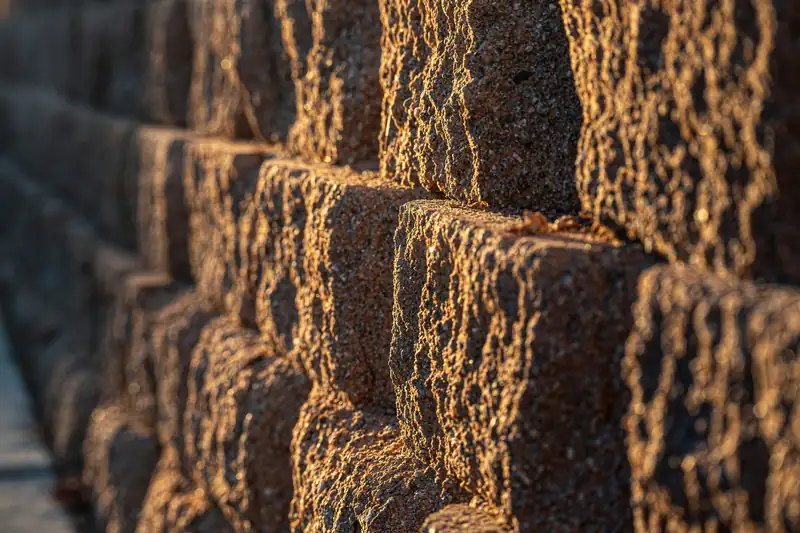 Stacked split-face concrete block retaining wall in low evening sun