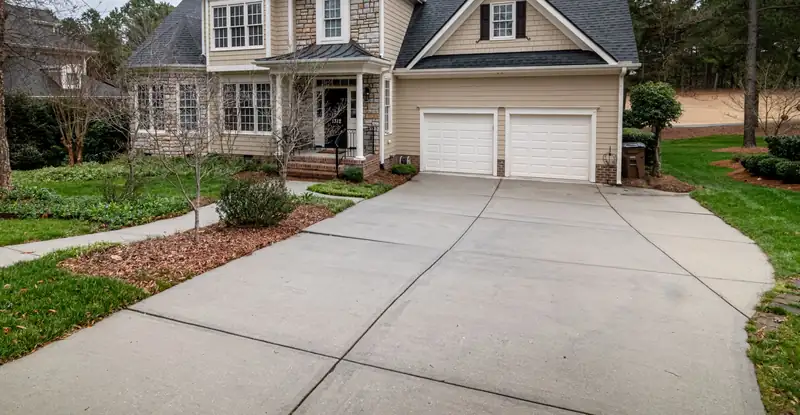 Wide curved concrete driveway leading to a two-car garage on a suburban lot