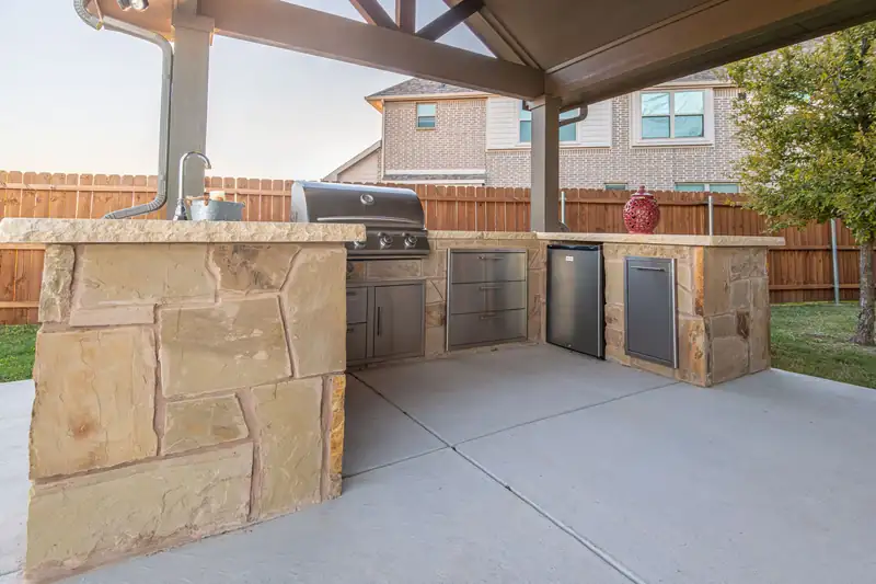Covered patio with a stone outdoor kitchen on a smooth gray concrete slab