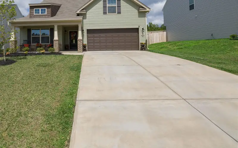 Long new concrete driveway running from the street to a suburban home
