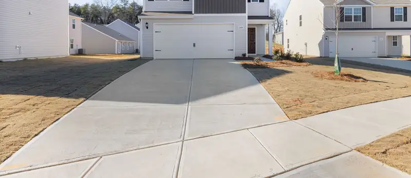 New broom-finished public sidewalk and driveway in front of a new-build home with fresh sod