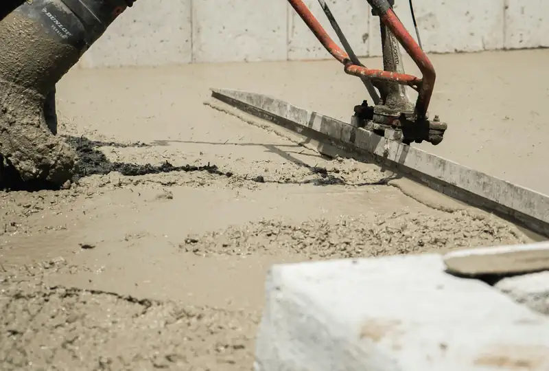 Worker running a vibratory power screed across fresh concrete