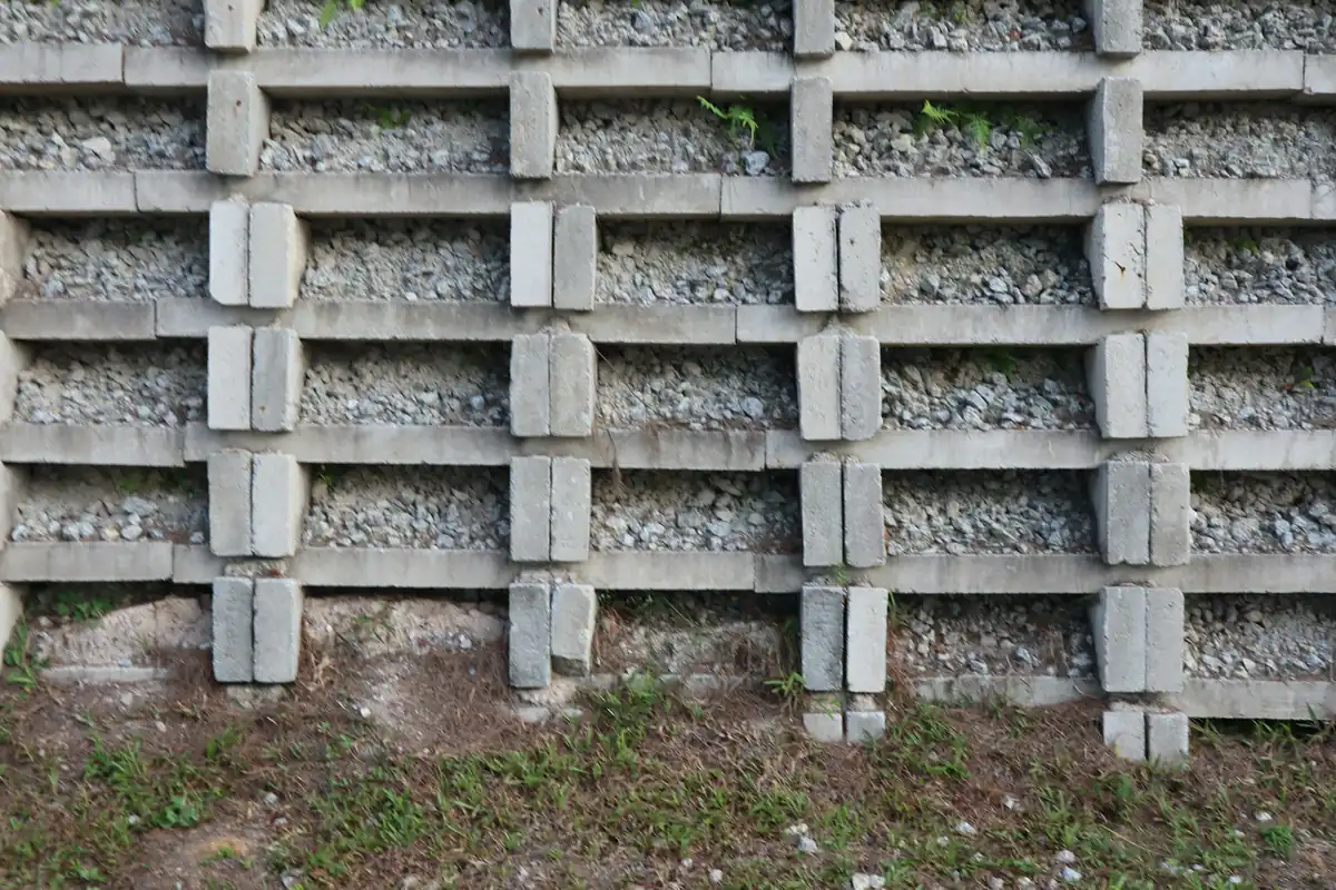 Concrete crib-style retaining wall with drainage gravel behind the units above a lawn